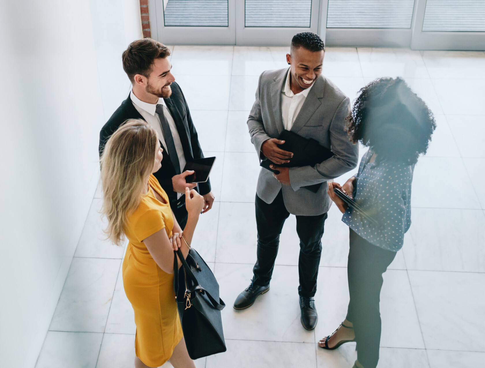 Group of young business professionals standing together and having casual discussing in office hallway. Business colleagues having casual meeting in office lobby.